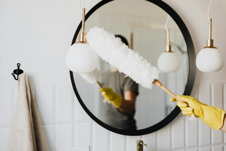 Crop woman dusting lamp during housework 