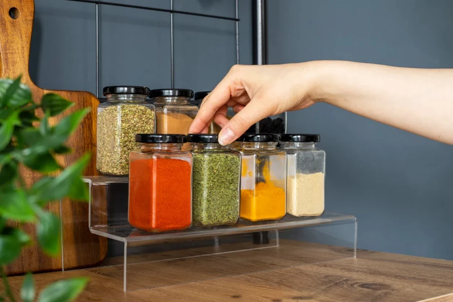 Cropped hand holding jar of spices on kitchen