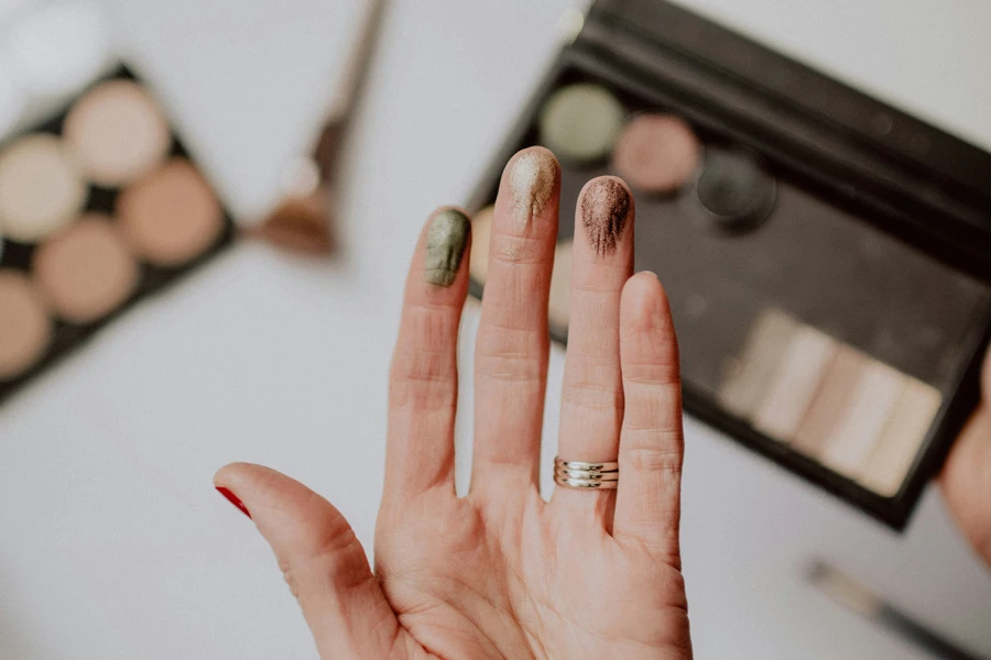 Different colors of eyeshadow testing on a woman's fingertips