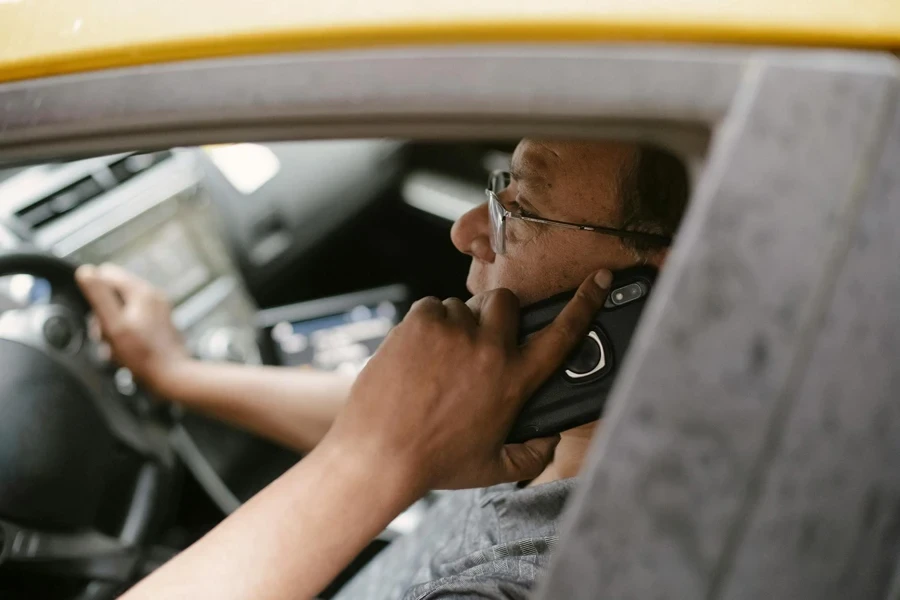 Ethnic man chatting on smartphone in car