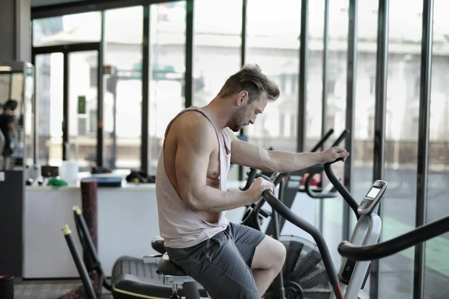 Exhausted athletic man training on exercise bike