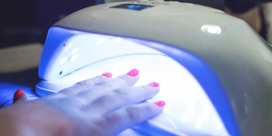 Female Hand with red nails in the lamp for manicure