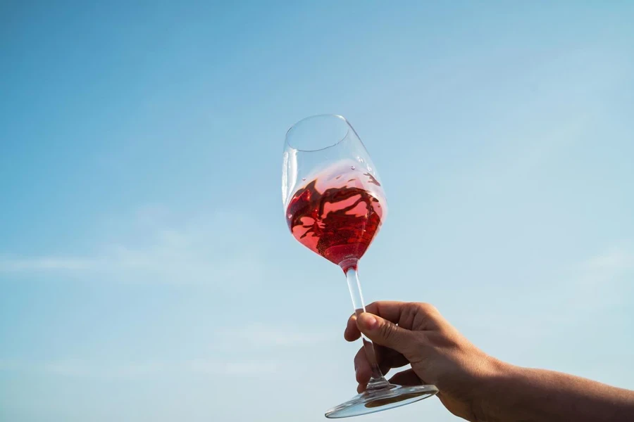 Female hand delicately holds a glass of rose wine