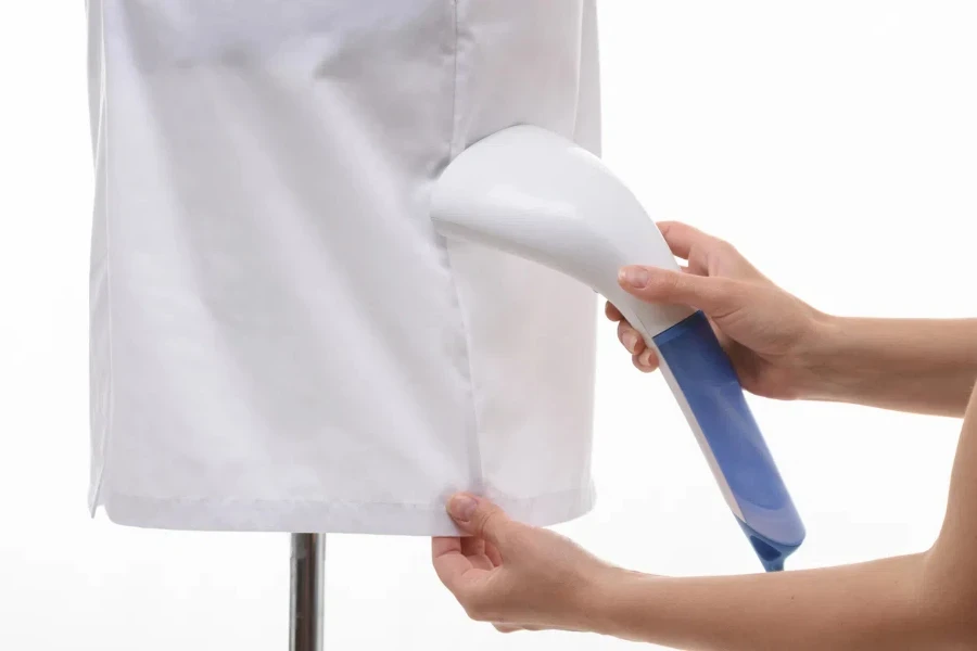 Female hands steaming a medical gown with a steamer