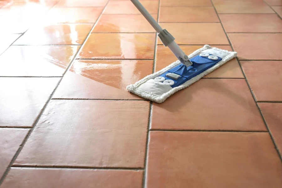 Flat wet-mop made of microfiber wipes the tiled terracotta floor