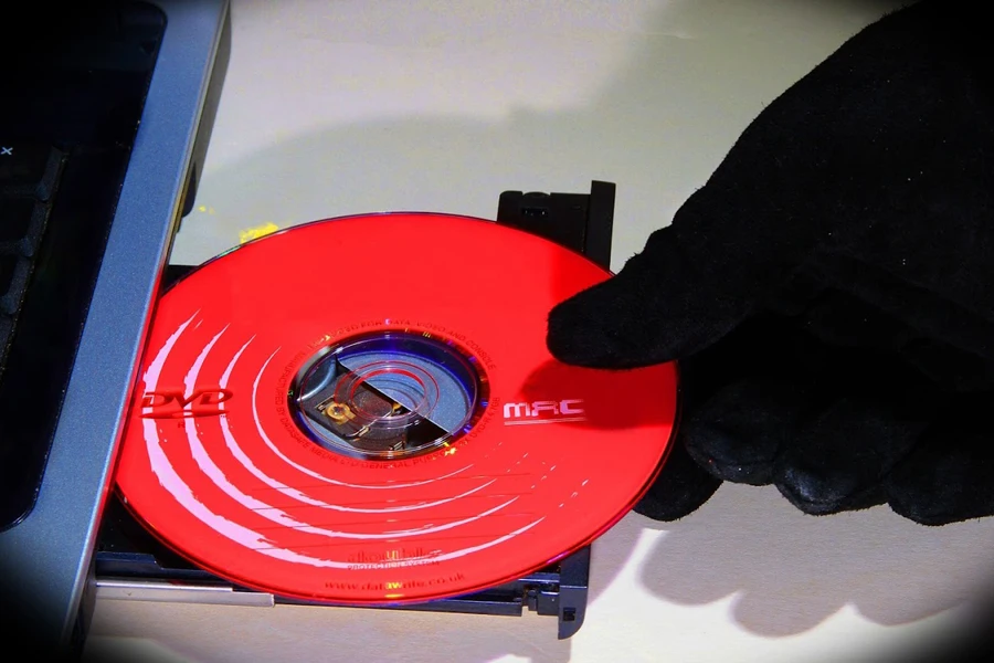 Hand putting a red DVD on an optical drive