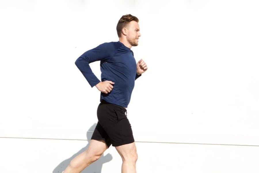 Happy man running outside against white wall