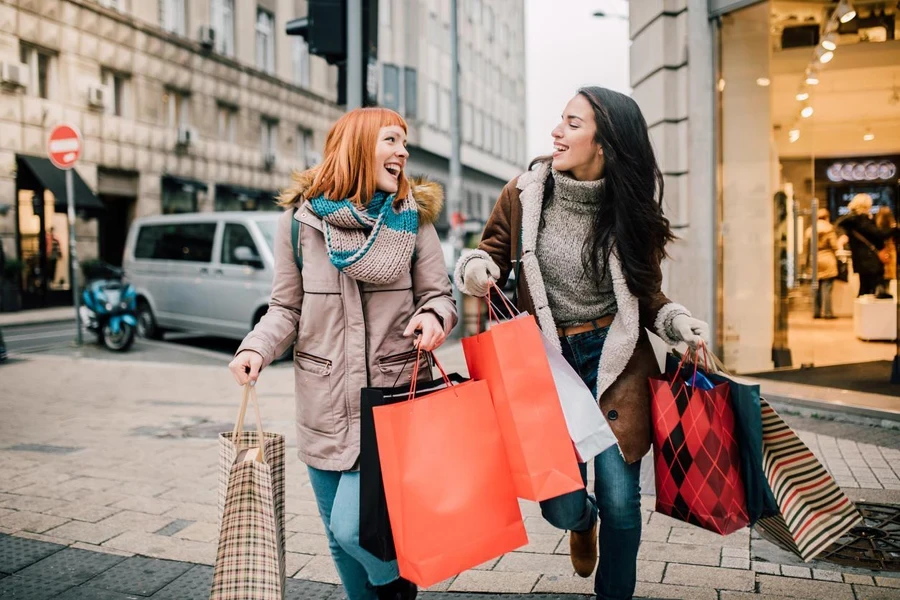 Happy two girls holding bunch of shopping bags