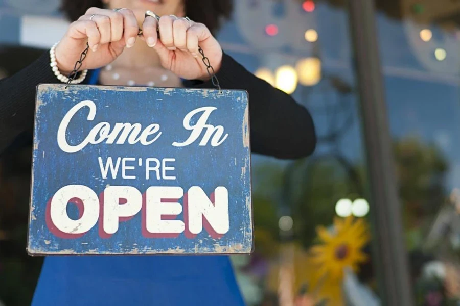 Lady holding a “Come in we're open” sign