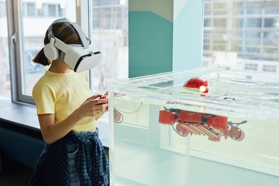 Little girl wearing VR goggles and exploring new robot with controllers