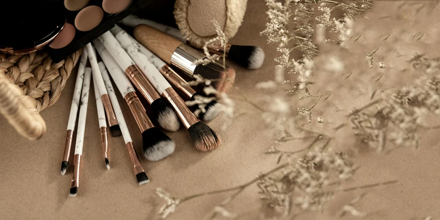 Makeup brushes with eyeshadows on beige surface