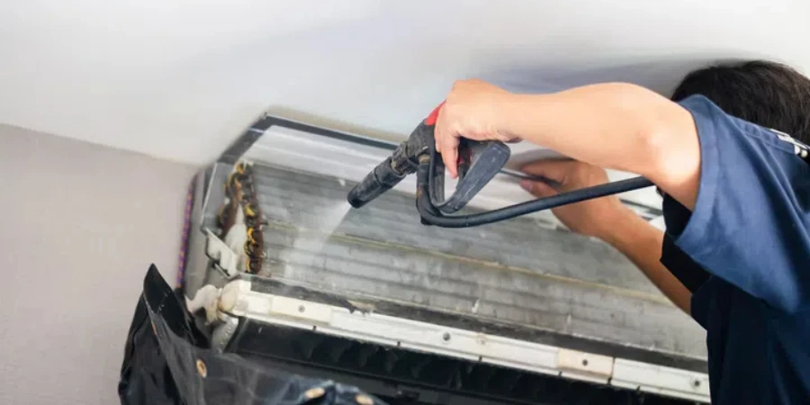 Male technician cleaning air conditioner indoors