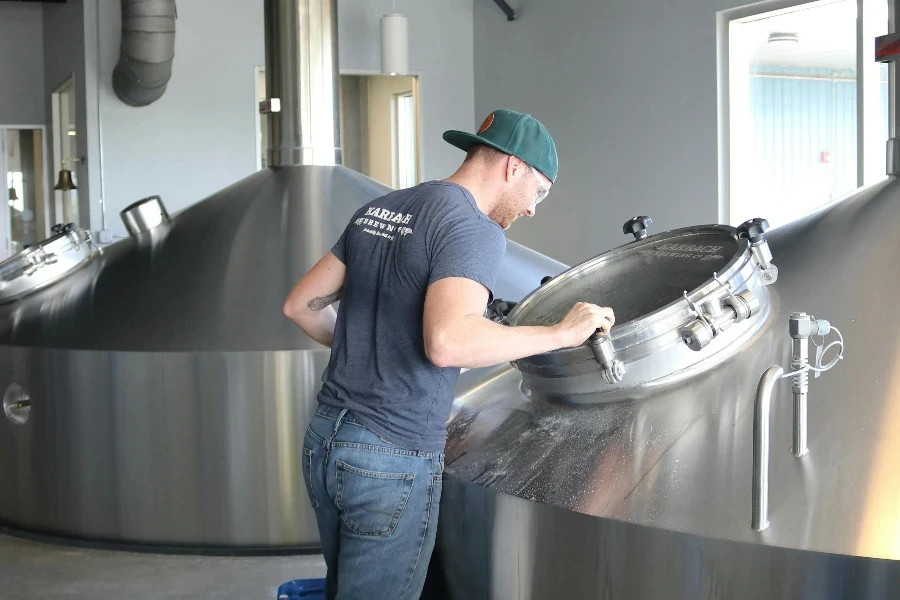 Man Wearing Gray T-shirt and Blue Jeans Looking at Stainless Steel Container