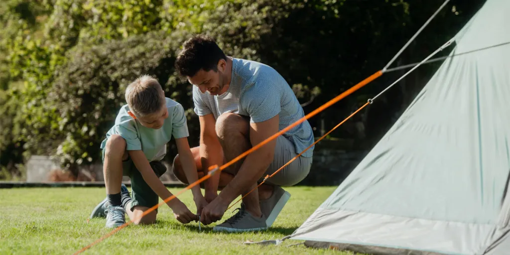 Man and son pushing a tent peg into the ground