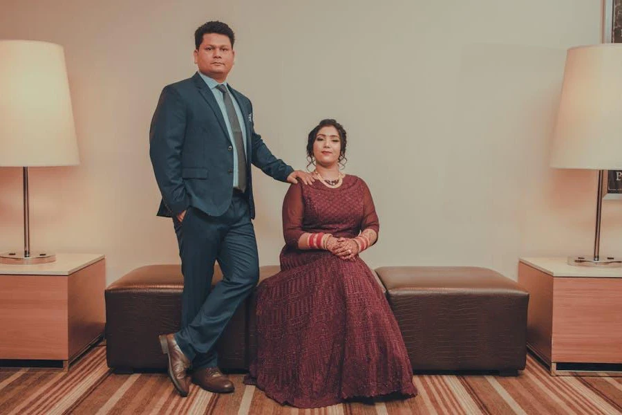 Man and woman posing in black-tie wedding guest outfits