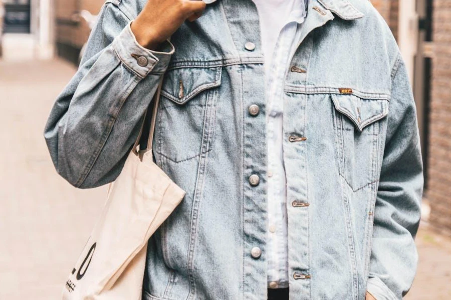 Man holding a tote bag in a light denim jacket