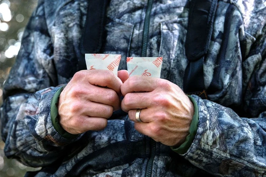 Man holding two packets of hand warmers