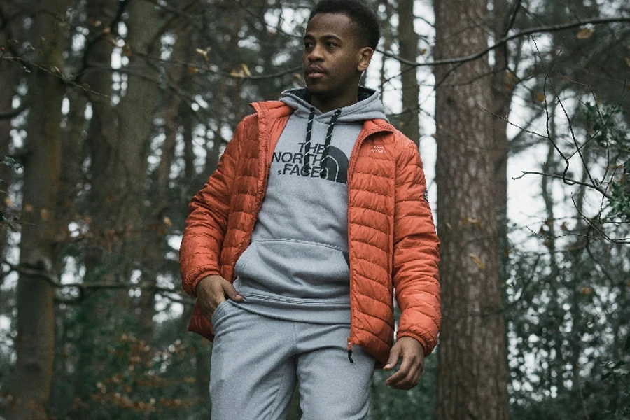 Man in gray sweatsuit with orange puffer coat