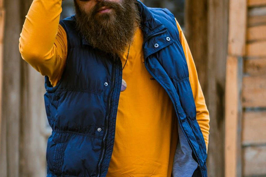 Man layering a blue down vest over a yellow tee