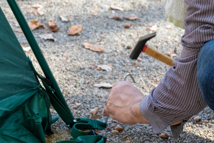 Man nailing a tent peg to the ground