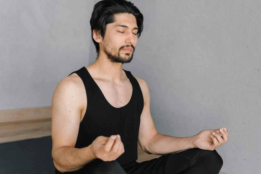 Man wearing a black tank top meditating
