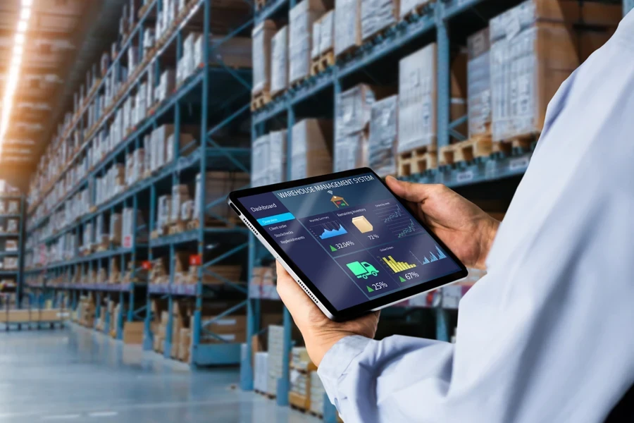 Manager using digital tablet,showing warehouse software management dashboard on blurred warehouse as background