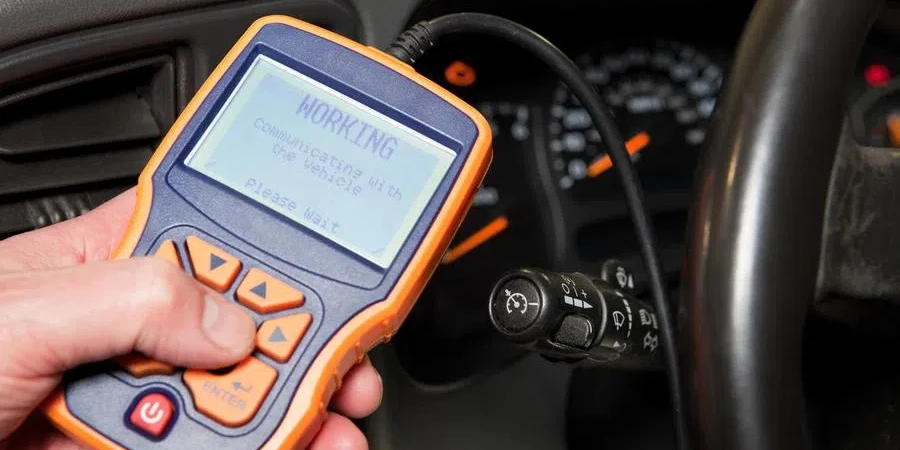 Mechanic Holding OBD Scanner near SUV Dashboard