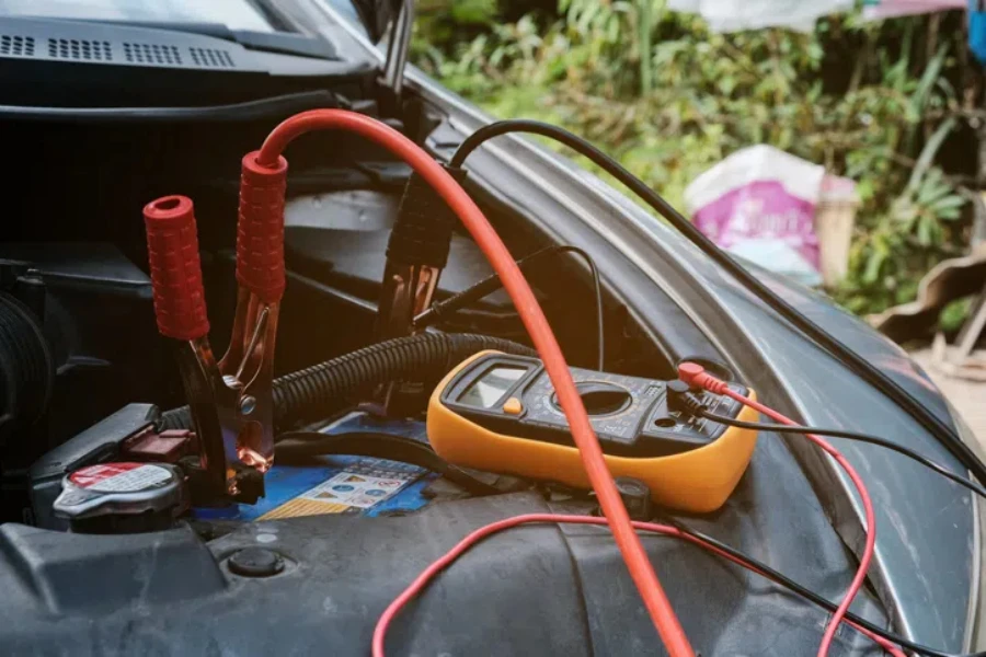 Mechanicl man uses electric multimeter voltmeter to check the voltage level maintenance car battery