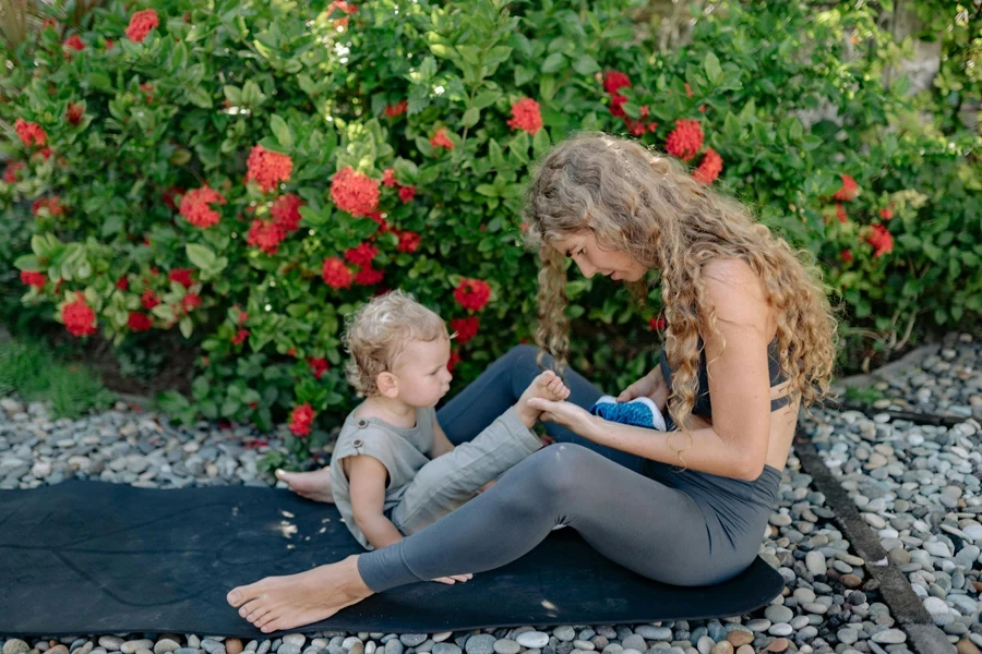 Mother and son resting on yoga mat in garden