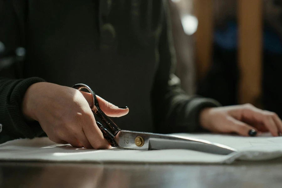 person holding a pair of scissors to cut the cloth