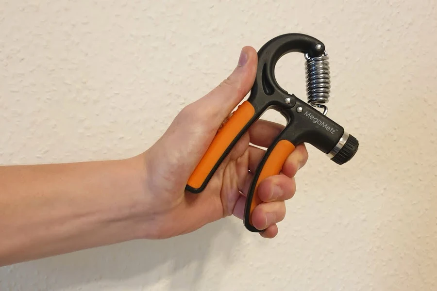 Person holding an orange and black grip trainer