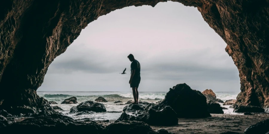 Photo of Man Standing on Rock Near Seashore