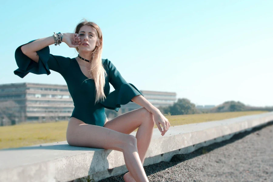 Photo of Woman in Green Bodysuit Sitting on Cement Pavement