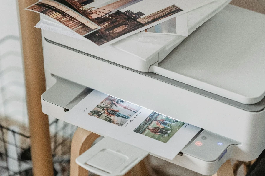 Photos placed on printer near table with cup of coffee