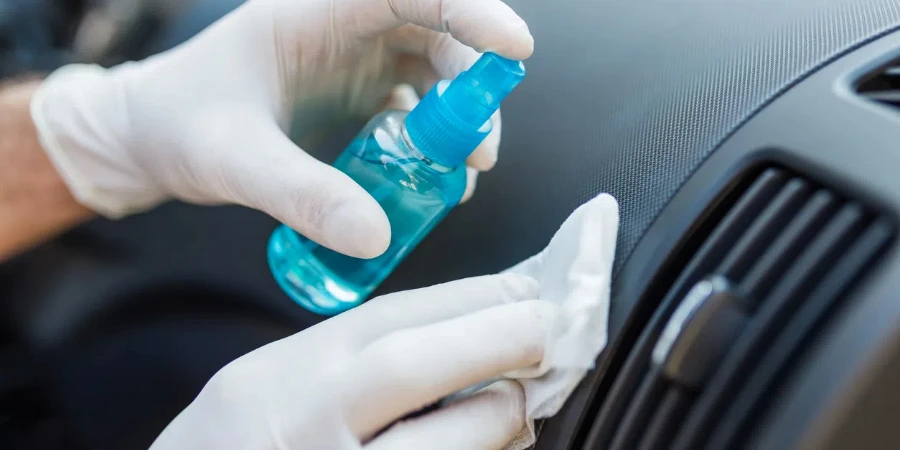 Professional worker using disinfectant and microfiber cloth to clean car interior