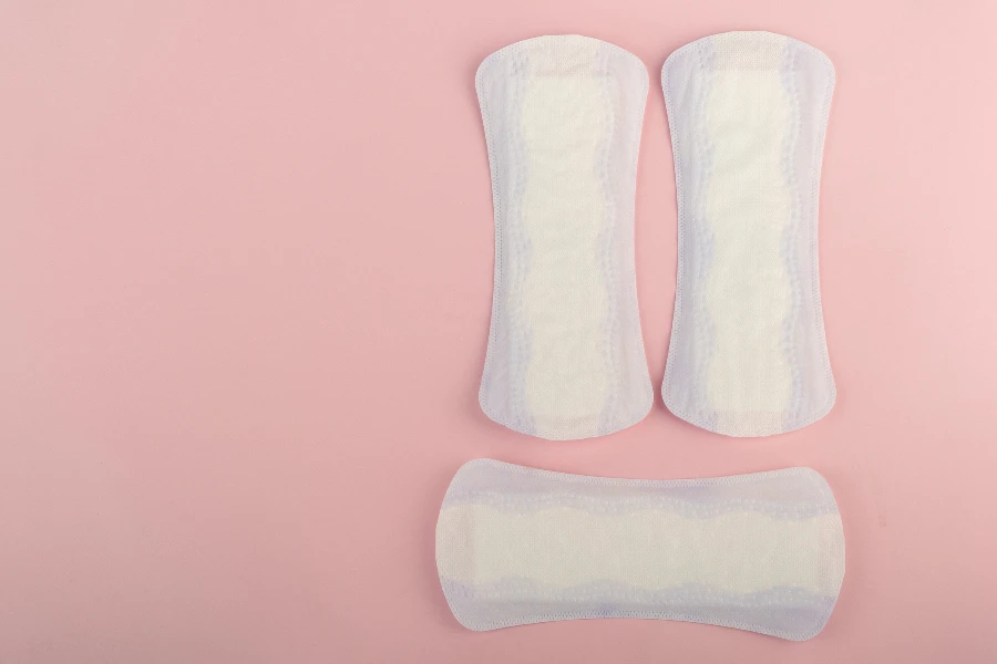 Purple and white feminine sanitary pads on a pink background