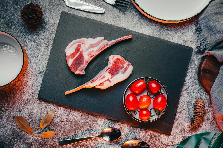 Raw Meat on Black Round Plate Beside Red Tomatoes on Black Wooden Table