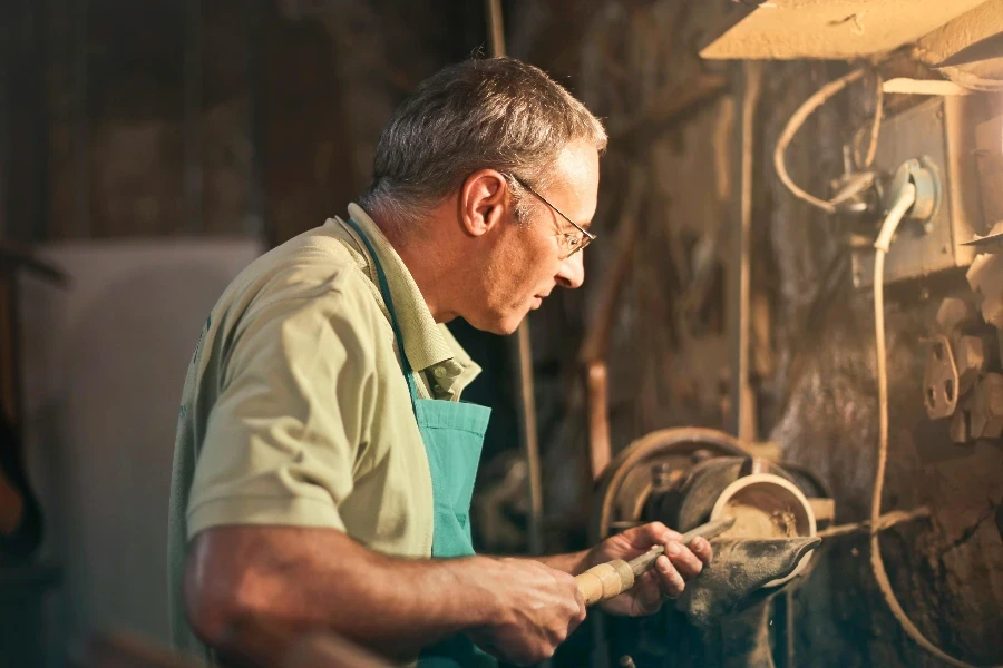 Senior male turner working on lathe machine in workshop