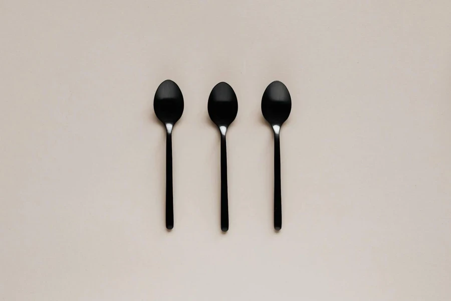 Set of black teaspoons on beige surface