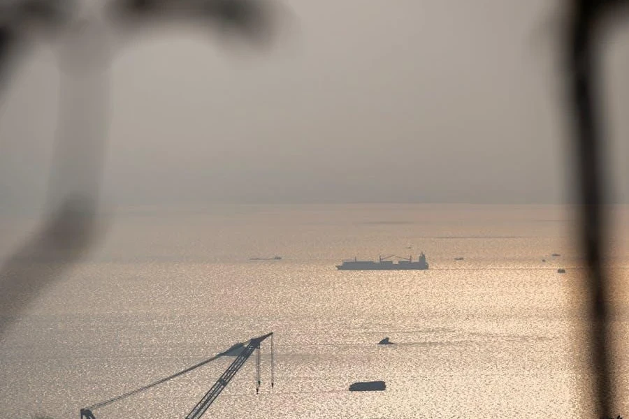 Silhouetted ships and cranes in a port at sunset