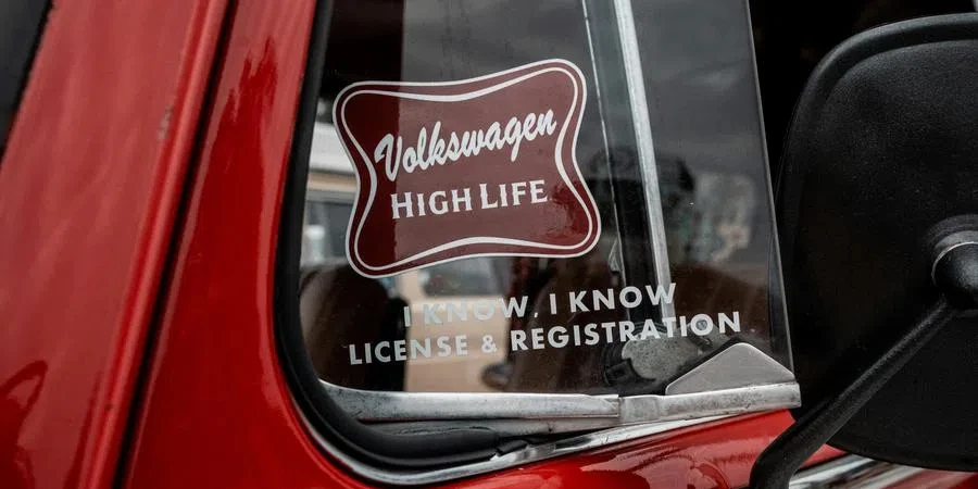 Stickers on the Vent Window of a Red Classic Volkswagen Beetle by ALTEREDSNAPS