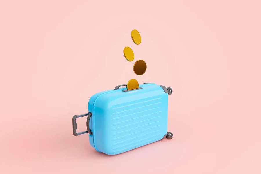Suitcase shaped money box with golden coins against pink background
