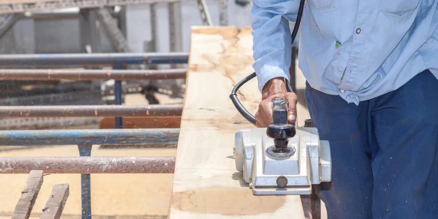 The carpenter planing log by using electric planer