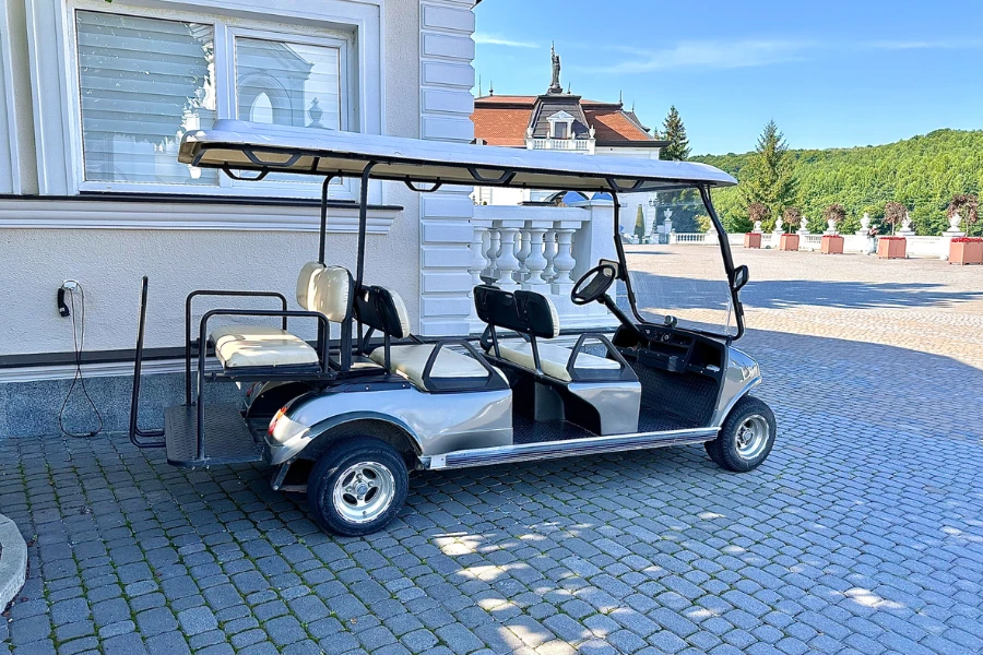 The golf cart is parked at an electric charging station in the yard near the hotel