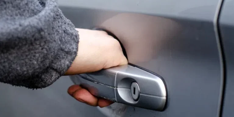 The man's hand opens the door of the silver-colored car