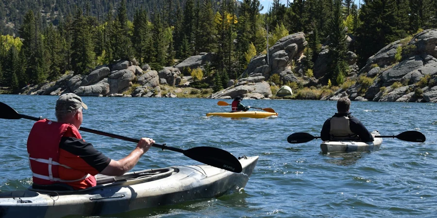 Three Men Riding Kayaks On Body Of Water