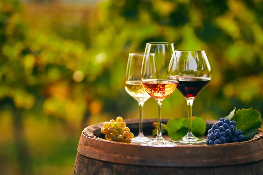 Three glasses of white, rose and red wine on a wooden barrel