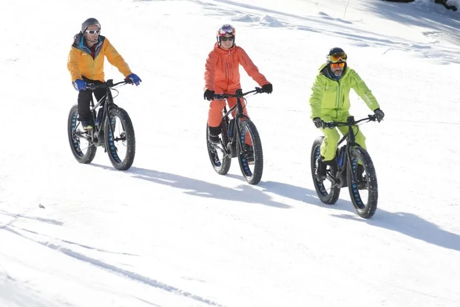 Three people snow biking in reflective clothing