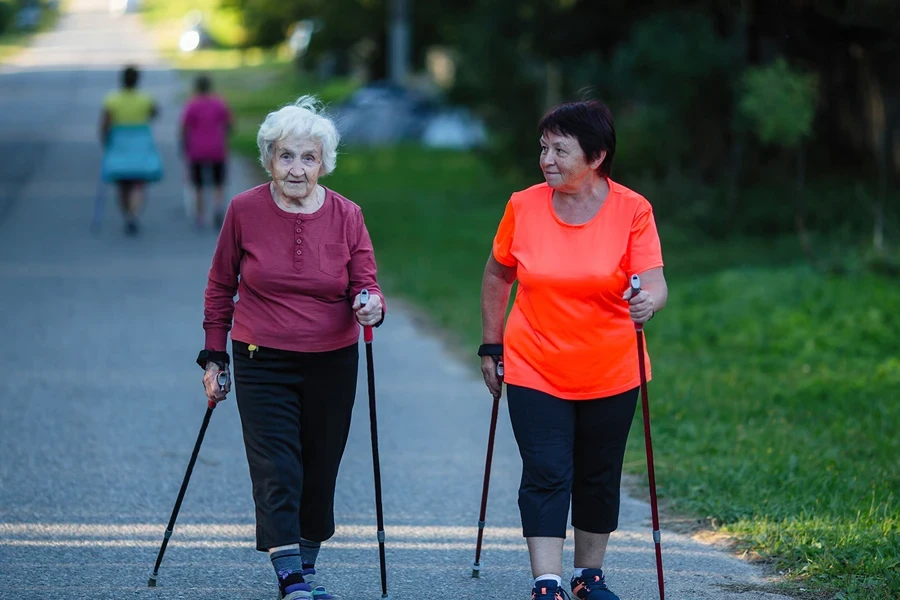 Two elderly women trekking with walking poles