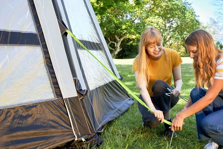 Two ladies setting up a tent with pegs